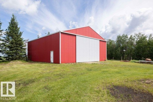 Red metal outbuilding with a gambrel roof and white sliding door - 58505 Rng Rd 260, Rural Westlock County, AB 