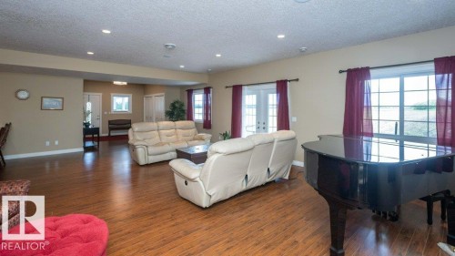 Spacious living area featuring wood-finish flooring, recessed lighting, and ample natural light from multiple windows - 58505 Rng Rd 260, Rural Westlock County, AB 