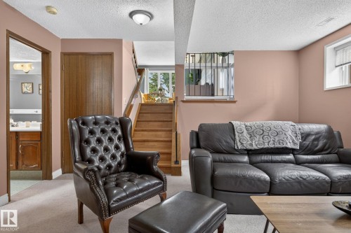 Finished lower level featuring a staircase with wood treads, a security-barred window, and a door leading to a bathroom with a wood-finish vanity - 14612 29 Street Nw, Edmonton, AB 