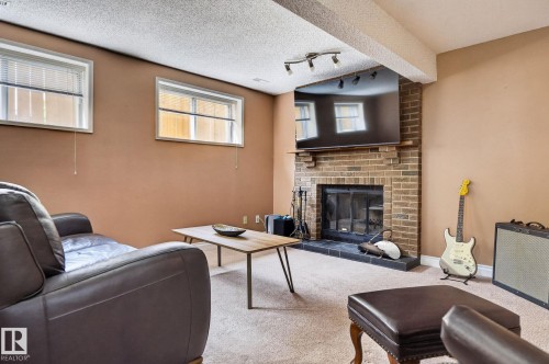 Brick-surround fireplace with a slate hearth, complemented by a textured ceiling and recessed lighting - 14612 29 Street Nw, Edmonton, AB 