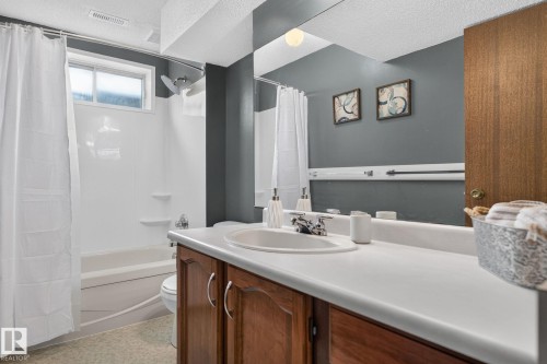 Bathroom featuring a wood-finish vanity with an integrated sink and a large mirror - 14612 29 Street Nw, Edmonton, AB 