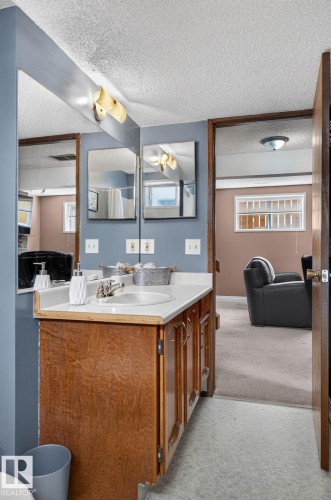 Vanity area featuring a wood-finish cabinet, integrated sink, and laminate countertop - 14612 29 Street Nw, Edmonton, AB 