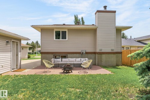 Expansive backyard featuring a red brick paver patio, a partial privacy fence, and a detached garage with direct patio access - 14612 29 Street Nw, Edmonton, AB 