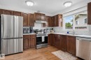 Kitchen featuring wood-finish flooring, dark wood cabinetry, and stainless steel appliances - 14612 29 Street Nw, Edmonton, AB 