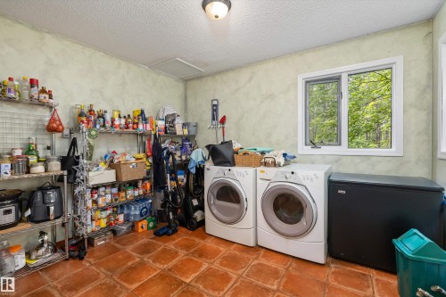 Utility room featuring terracotta-style tile flooring, textured wall finish, and a window providing natural illumination - 7 53424 Range Road 13, Rural Parkland County, AB 