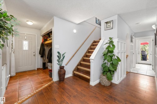 Entryway featuring wood-finish flooring, terracotta tile, a wood staircase with white risers, and wainscoting detail - 7 53424 Range Road 13, Rural Parkland County, AB 