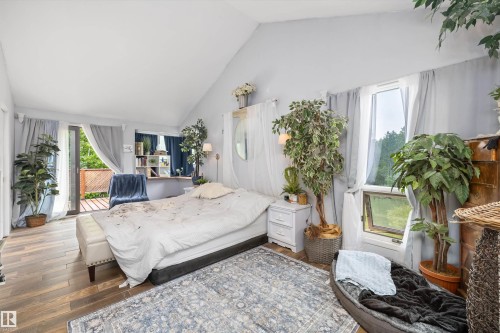 Vaulted ceiling bedroom featuring wood-finish flooring and direct access to an outdoor deck - 7 53424 Range Road 13, Rural Parkland County, AB 
