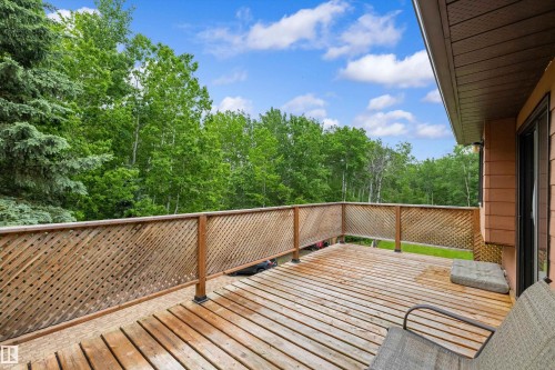 Expansive wood deck with lattice railing, surrounded by mature trees - 7 53424 Range Road 13, Rural Parkland County, AB 