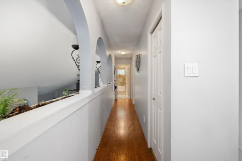 Hallway featuring wood-finish flooring and a built-in planter with arch details - 7 53424 Range Road 13, Rural Parkland County, AB 