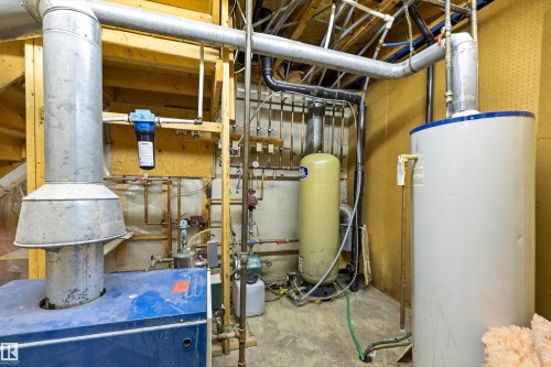 Utility area featuring a water heater, water treatment tank, and furnace with extensive plumbing and ductwork - 7 53424 Range Road 13, Rural Parkland County, AB 