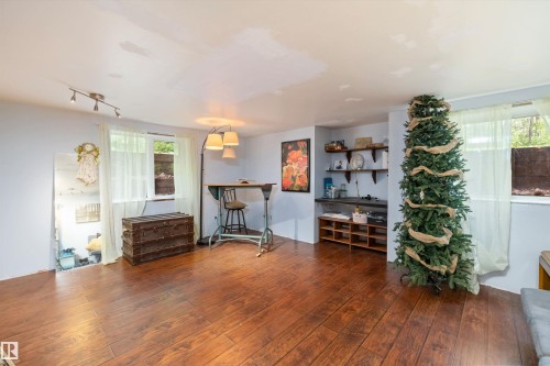 Spacious room featuring wood-finish flooring, two windows, track lighting, and built-in shelving - 7 53424 Range Road 13, Rural Parkland County, AB 