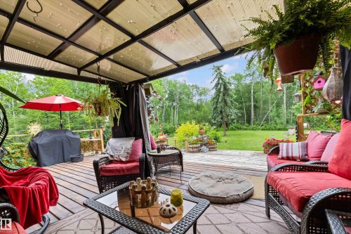 Covered outdoor deck with a transparent roof, wood deck flooring, and a spacious grassy area beyond - 7 53424 Range Road 13, Rural Parkland County, AB 