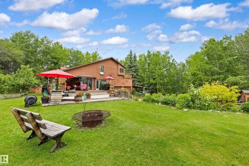 Spacious lawn area featuring a fire pit and a rustic wooden bench - 7 53424 Range Road 13, Rural Parkland County, AB 
