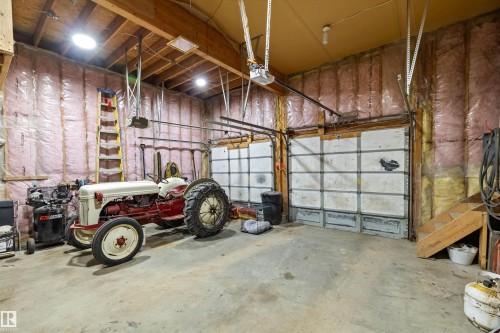 Spacious garage featuring exposed wood beam ceilings and two insulated garage doors - 7 53424 Range Road 13, Rural Parkland County, AB 