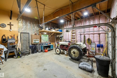 Spacious garage featuring exposed wood beams, concrete flooring, and an overhead garage door track system - 7 53424 Range Road 13, Rural Parkland County, AB 