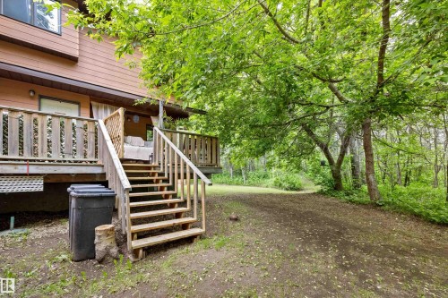 Wood-sided exterior featuring a spacious wood deck with staircase access to the grounds - 7 53424 Range Road 13, Rural Parkland County, AB 