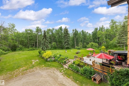 Multi-level wood deck with lattice railing, featuring steps descending to a sprawling lawn - 7 53424 Range Road 13, Rural Parkland County, AB 