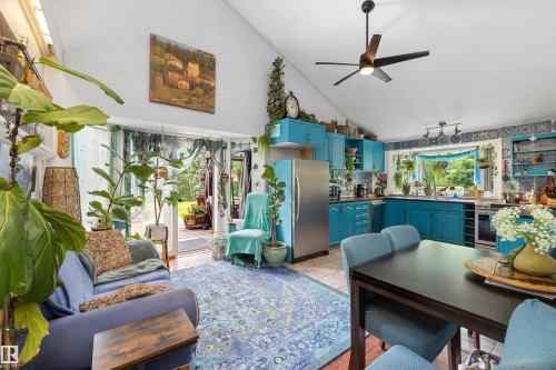 Vaulted ceilings highlight this open-concept space featuring a vibrant kitchen with teal cabinetry and stainless steel appliances - 7 53424 Range Road 13, Rural Parkland County, AB 