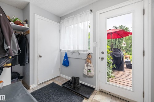Entryway featuring tiled flooring, built-in shelving, a full-light exterior door, and a transom window with privacy curtain - 7 53424 Range Road 13, Rural Parkland County, AB 