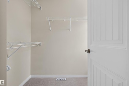 Organized walk-in closet featuring wire shelving, hanging rods, and light-toned carpeting - 6928 22 Avenue, Edmonton, AB 