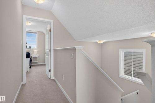 Carpeted hallway with a neutral wall palette, white trim, and a ceiling light fixture - 6928 22 Avenue, Edmonton, AB 