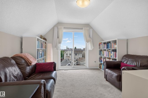 Dormer room featuring a sliding glass door and balcony, neutral carpeting, and sloped ceilings - 6928 22 Avenue, Edmonton, AB 