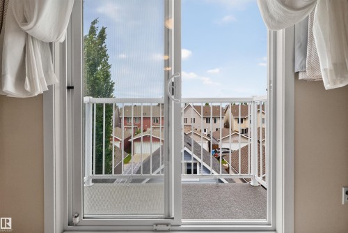 Sliding glass door opening to an outdoor balcony featuring a white metal railing and composite decking - 6928 22 Avenue, Edmonton, AB 