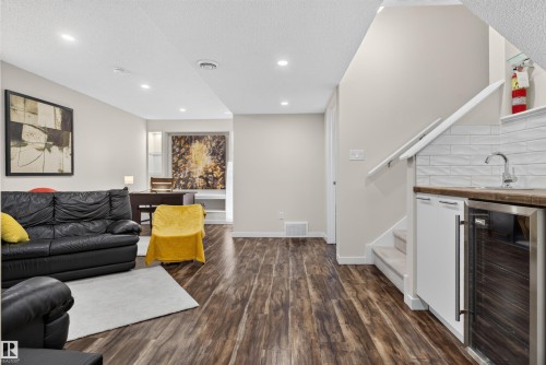 Finished lower level featuring wood-finish flooring, recessed lighting, and a built-in wet bar with a stainless steel beverage refrigerator - 6928 22 Avenue, Edmonton, AB 
