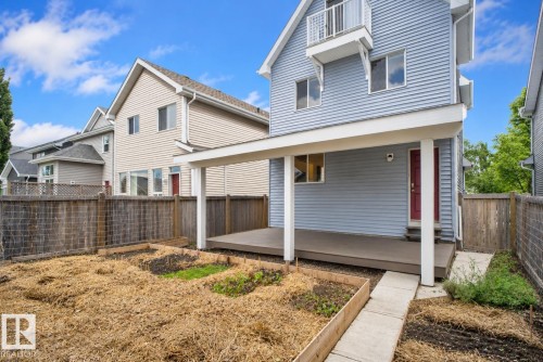 Rear exterior with a covered deck, light blue siding, and a red entry door - 6928 22 Avenue, Edmonton, AB 