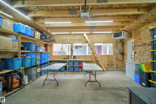 Spacious utility room featuring an exposed wood beam ceiling, concrete flooring, and multiple windows providing natural light - 6928 22 Avenue, Edmonton, AB 