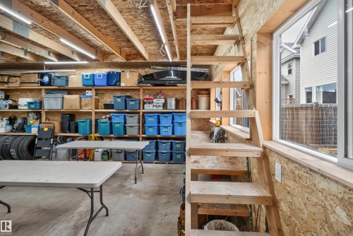 Utility space featuring exposed wood beam ceiling, strip lighting, built-in shelving, concrete flooring, and a natural wood staircase - 6928 22 Avenue, Edmonton, AB 