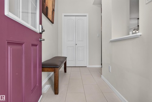 Entryway featuring a panel door with an upper glass insert, tile flooring, and white baseboards - 6928 22 Avenue, Edmonton, AB 