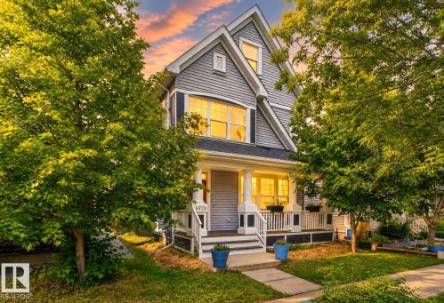 Light gray siding exterior with dark shutters, covered front porch, white column supports, and a prominent front gable - 6928 22 Avenue, Edmonton, AB 