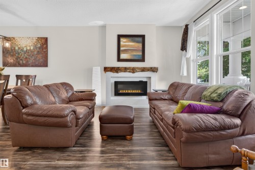 Living area featuring wood-finish flooring and a central fireplace with an ornate wood mantel - 6928 22 Avenue, Edmonton, AB 