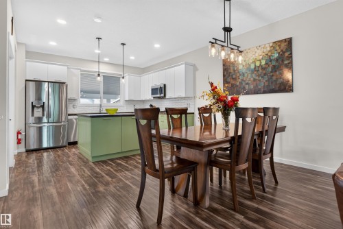 Open-concept dining area and kitchen featuring wood-finish flooring - 6928 22 Avenue, Edmonton, AB 