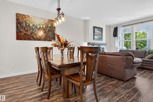 Open-concept living space featuring wood-finish flooring, recessed lighting, and a modern chandelier - 6928 22 Avenue, Edmonton, AB 