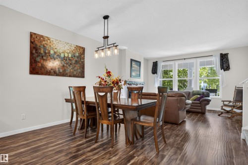 Dining area featuring wood-finish flooring, a contemporary chandelier, and ample natural light from multiple windows - 6928 22 Avenue, Edmonton, AB 