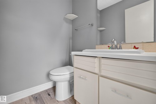 Bathroom featuring wood-finish flooring, a white toilet, and a vanity with a white countertop and chrome faucet - 178 Tudor Lane, Edmonton, AB 
