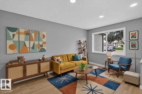 Spacious living area featuring light wood-finish flooring, recessed lighting, a large window, and a built-in trim detail along the lower wall - 178 Tudor Lane, Edmonton, AB 