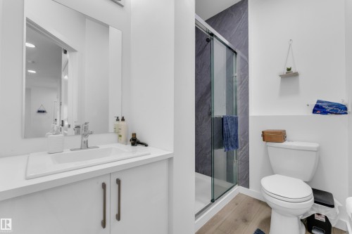 Bathroom featuring a sleek white vanity with integrated sink, chrome faucet, and rectangular mirror - 432 29 Street, Edmonton, AB 