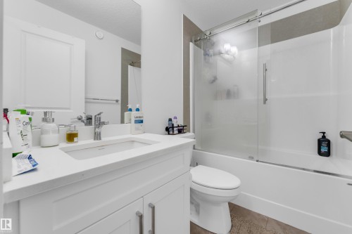 Contemporary bathroom featuring a white vanity with an integrated sink, polished chrome faucet, and mirrored medicine cabinet - 432 29 Street, Edmonton, AB 