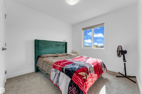 Bedroom featuring a single window with a roller shade, light-colored carpeting, and white painted walls - 432 29 Street, Edmonton, AB 