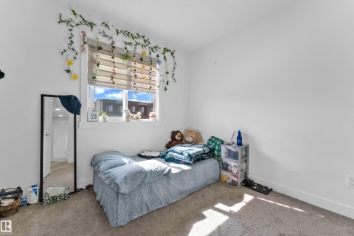 Carpeted bedroom featuring a large window with horizontal blinds, white walls, and white baseboards - 432 29 Street, Edmonton, AB 