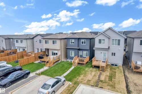 Newly constructed row of modern homes featuring multi-level decks with wooden railings, private fenced yards, and a designated parking area - 432 29 Street, Edmonton, AB 