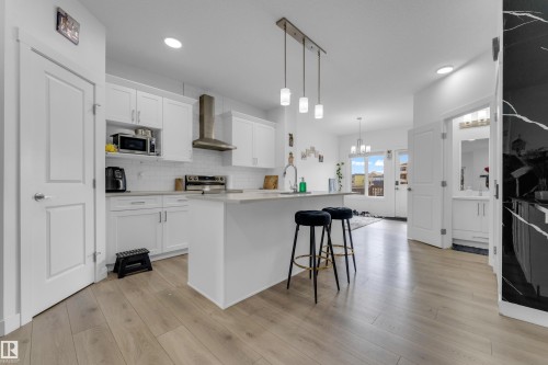 Modern kitchen featuring white shaker cabinetry, stainless steel appliances, and a light-toned wood-finish flooring - 432 29 Street, Edmonton, AB 