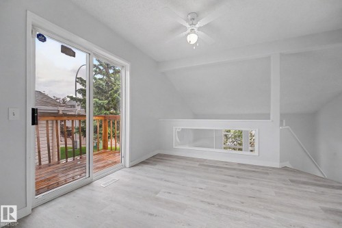 Room featuring light wood-finish flooring, white walls, and a sliding glass door opening to a wooden deck - 3704 39 Avenue, Edmonton, AB 