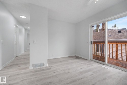 Spacious room featuring wood-finish flooring and a sliding glass door - 3704 39 Avenue, Edmonton, AB 
