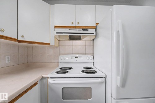 Kitchen featuring a white electric range, matching white refrigerator, and light-toned countertops - 3704 39 Avenue, Edmonton, AB 