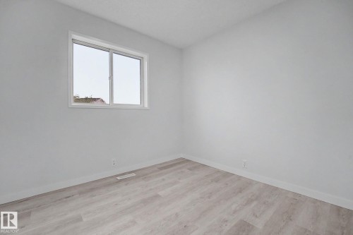 Room featuring light-toned wood-finish flooring, white baseboards, and a window with white trim - 3704 39 Avenue, Edmonton, AB 
