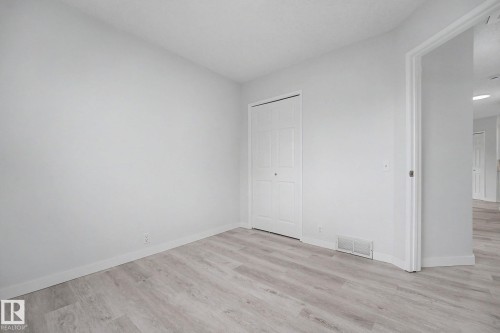 Room featuring wood-finish flooring, white baseboards, a bi-fold closet door, and a white wall finish - 3704 39 Avenue, Edmonton, AB 